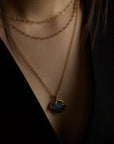 A closeup portrait of a woman model's neck wearing the cosmos pendant with a blue labradorite natural gemstone and the hearts labradorite double chain necklace. All jewelry are made of silver and gold vermeil. Demi-fine jewelry. Made in Athens, Greece, Europe,EU.