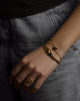 A closeup of a hand with jewelry. On the finger there is the aura ring with natural topaz gemstones. On the wrist there is the cosmos bracelet with natural black onyx gemstone and the ascension cuff with natural black onyx gemstone. All jewelry are made of silver and gold vermeil. Demi-fine jewelry. Made in Athens, Greece, Europe,EU.