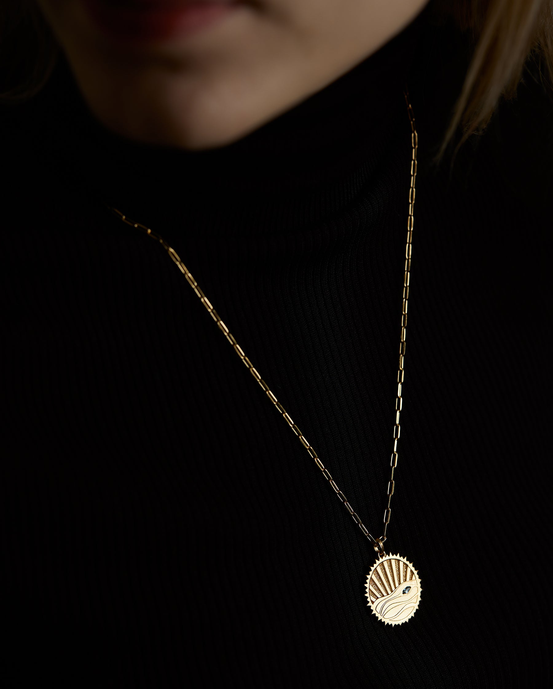 A closeup portrait of a woman model's neck wearing the aqua element necklace with a London blue topaz natural gemstone. All jewelry are made of silver and gold vermeil. Demi-fine jewelry. Made in Athens, Greece, Europe,EU.