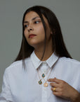 A portrait of a woman model wearing 3 necklaces. The soul necklace with a blue labradorite natural gemstone, the cosmos necklace with an aquamarine natural gemstone and the aer element necklace with an amethyst natural gemstone. On her ring she is wearing the messenger ring with a purple chalcedony natural gemstone. All jewelry are made of silver and gold vermeil. Demi-fine jewelry. Made in Athens, Greece, Europe,EU.